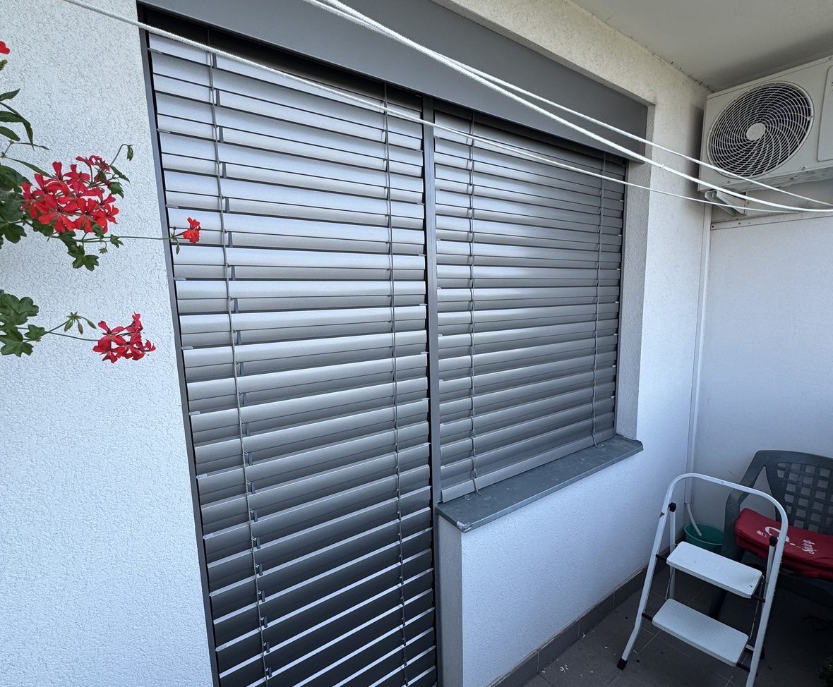 Venkovní žaluzie na zasklené lodžii s pelargoniemi