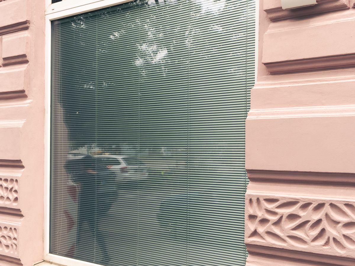 Stažená žaluzie za sklem okna zvenku